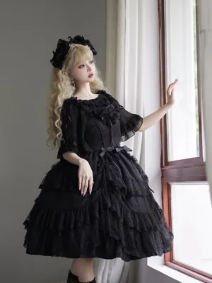 Black gothic lolita JSK jumper skirt half-body side view with sheer sleeves ruffled bodice waist bow layered tulle skirt indoor window setting