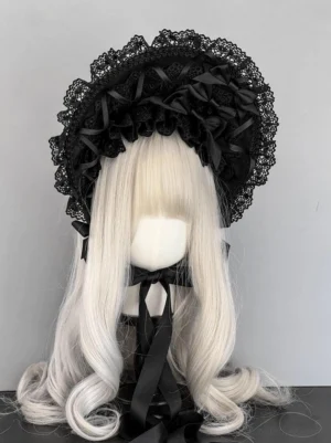 Black gothic lolita lace bonnet with wide ruffled brim, satin ribbon bows and rosettes, front view on mannequin head with platinum blonde curly wig