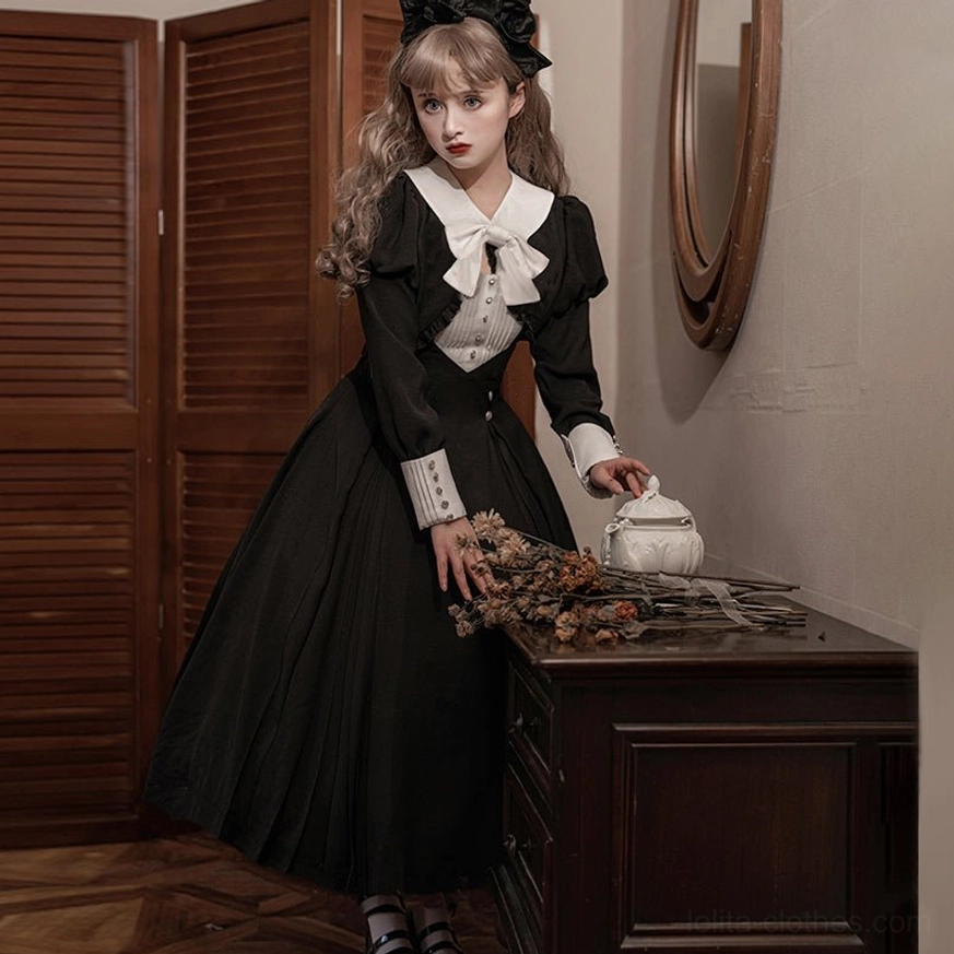 Side profile view of black Lolita OP dress showing high-waisted silhouette and pleated skirt design, model posing with vintage porcelain teapot in bedroom setting