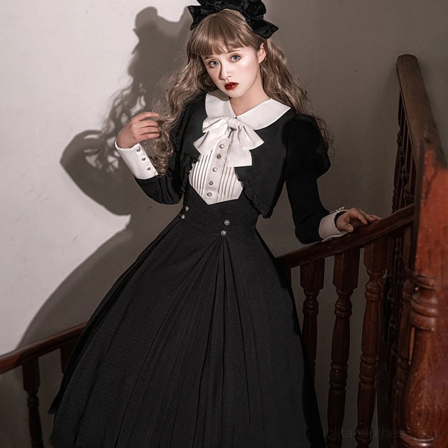 Black Gothic Lolita one-piece dress with white collar and large bow tie worn on vintage wooden staircase, featuring puffed long sleeves and pleated skirt with model wearing black hair bow