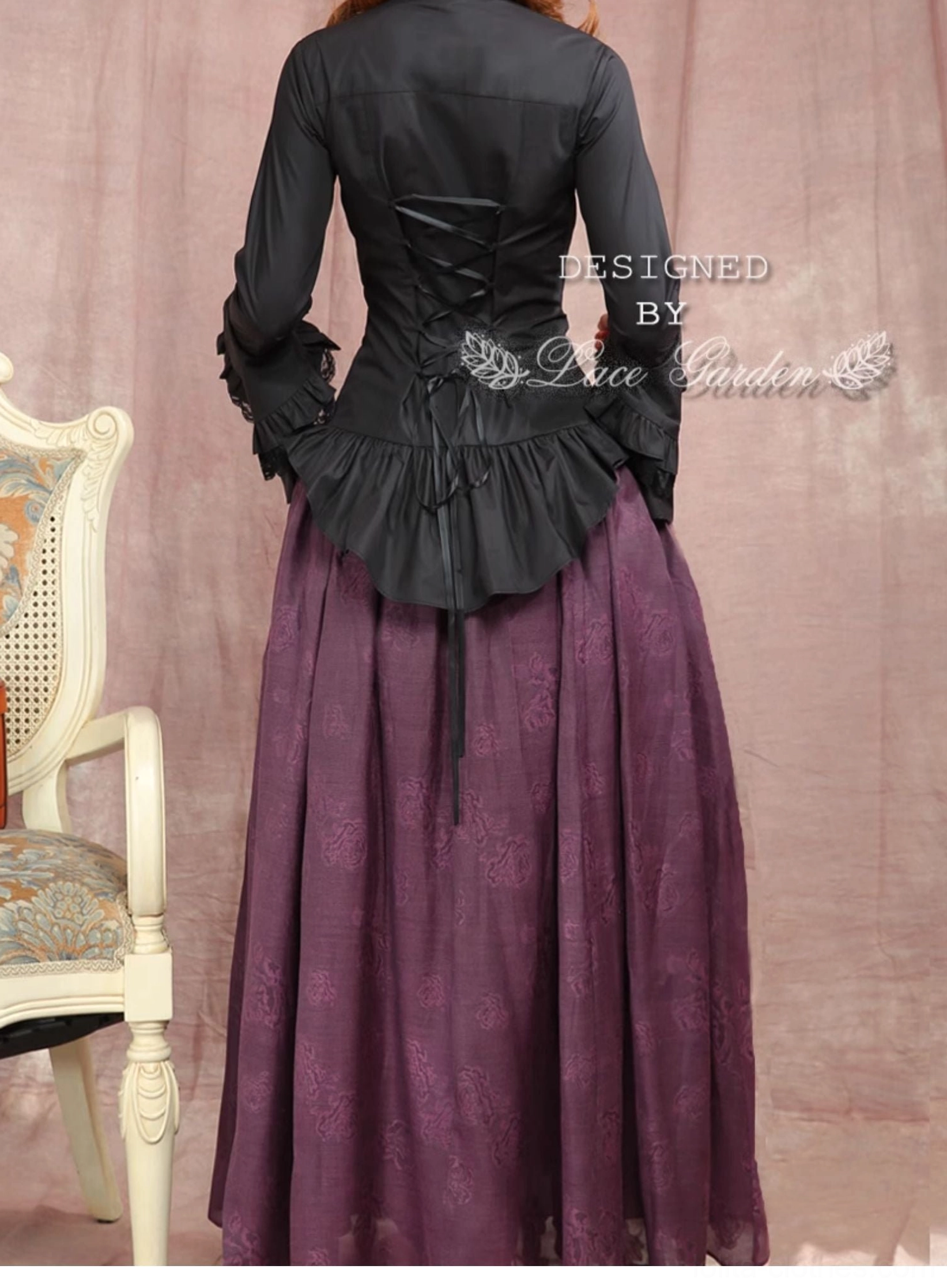Black gothic lolita ruffled blouse full back view, lace-up back closure ruffled peplum hem flared sleeves on female model vintage chair background
