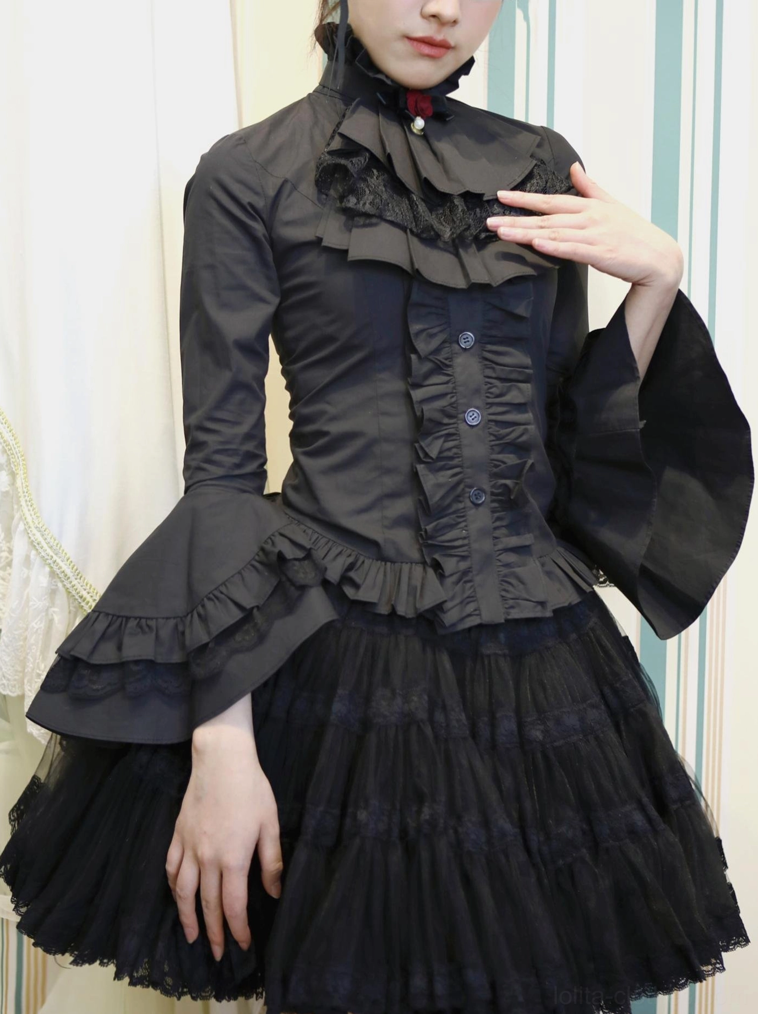 Black gothic lolita long-sleeve ruffled blouse with high stand collar and detachable jabot, front three-quarter view on female model wearing black tulle skirt