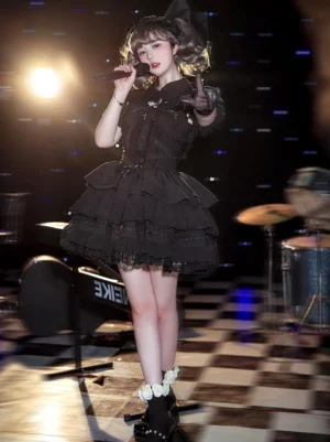 Black Gothic Lolita short dress with tiered ruffle skirt and black platform boots on performance stage with dramatic lighting