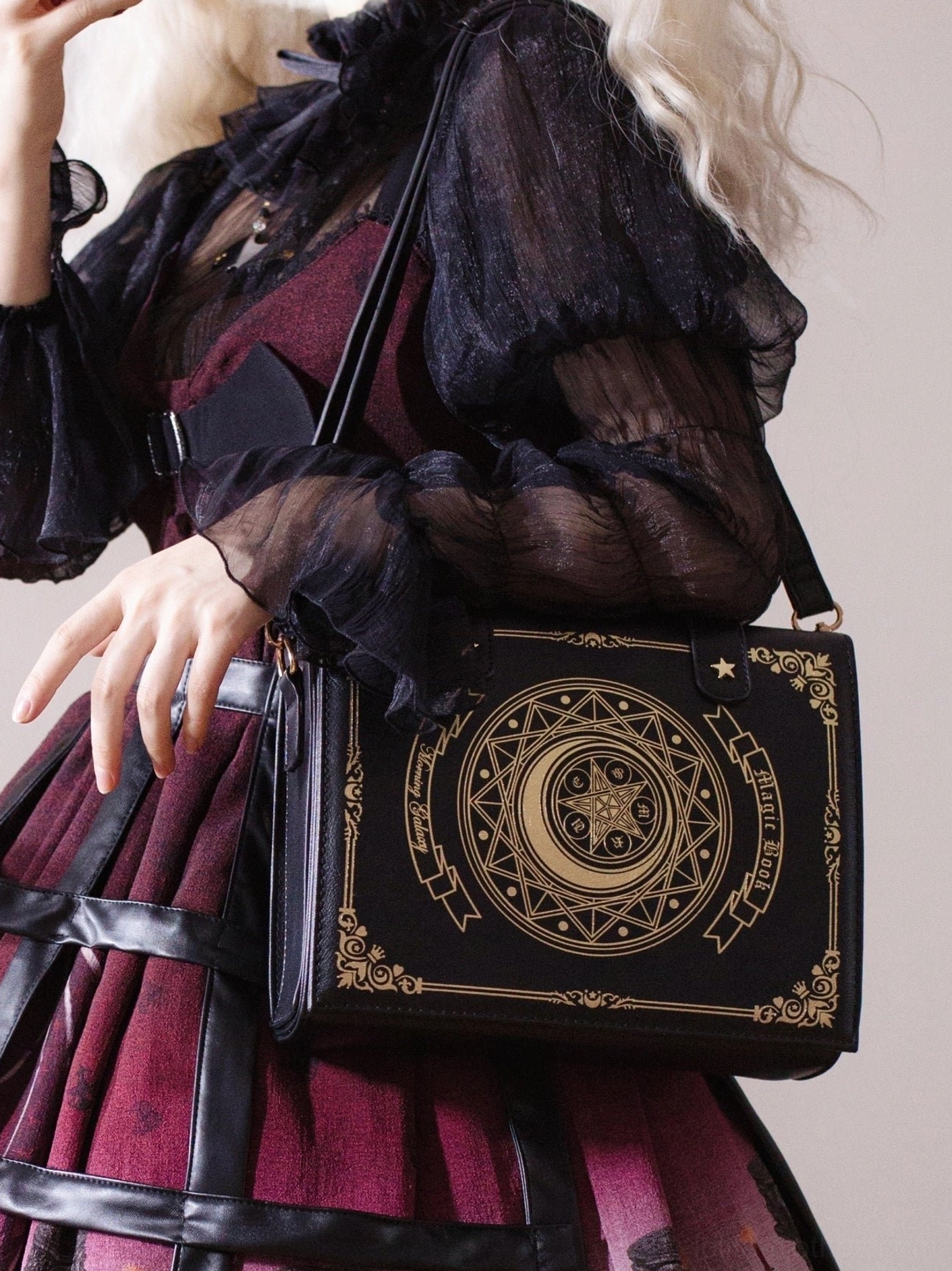 Black structured book-shaped lolita crossbody bag front view with intricate gold tarot pattern details and model in dark red lolita dress