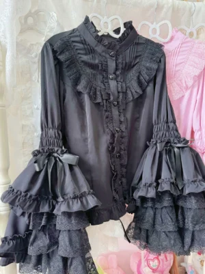 Black Gothic Sweet Lolita hime sleeve blouse with multi-layer lace ruffle bell sleeves, heart-shaped button placket, and bow-accented cuffs displayed on clothing rack