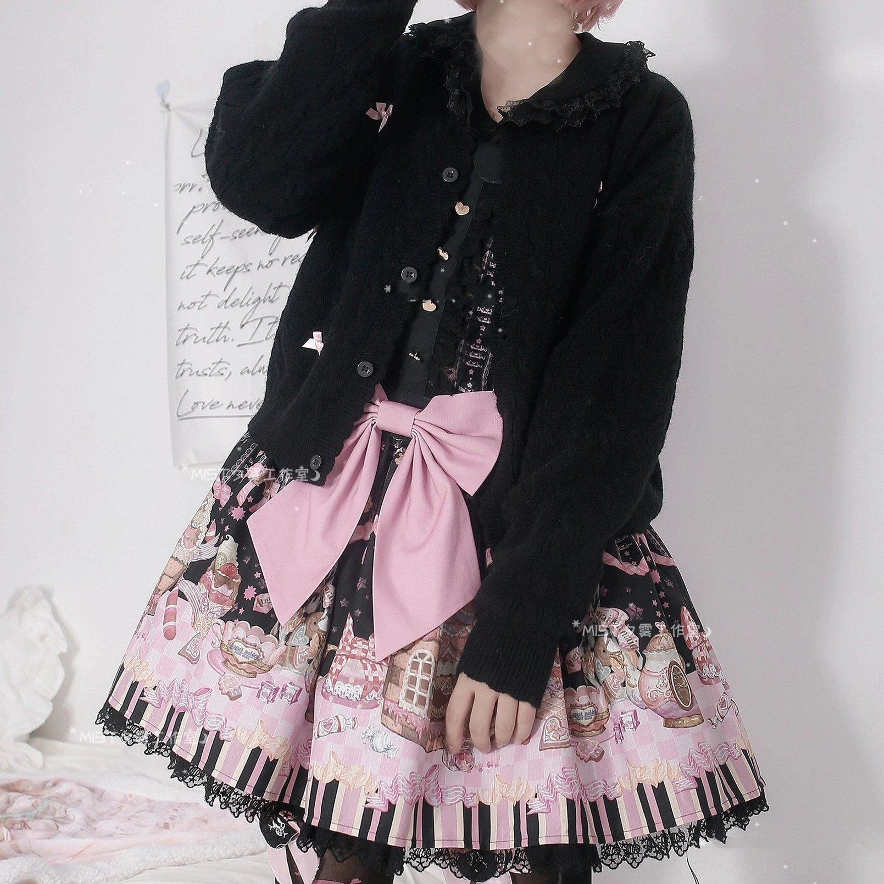 Black long sleeve Lolita cardigan with doll collar and single-breasted front closure worn with cartoon printed Lolita skirt, model half-body shot with pink bow waist accessory