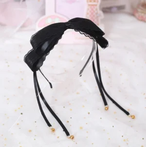 Black lace bell-tassel bow KC hair headband with golden bell charms and long satin ribbons, front oblique view on clear display stand against starry white background - delicate lolita headdress with ruffled butterfly bow design