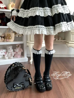 Jet black lace-trimmed sweet lolita knee-high socks with delicate bow accents, paired with black platform Mary Janes and black-white lolita coordinate, front overhead full lower-body view