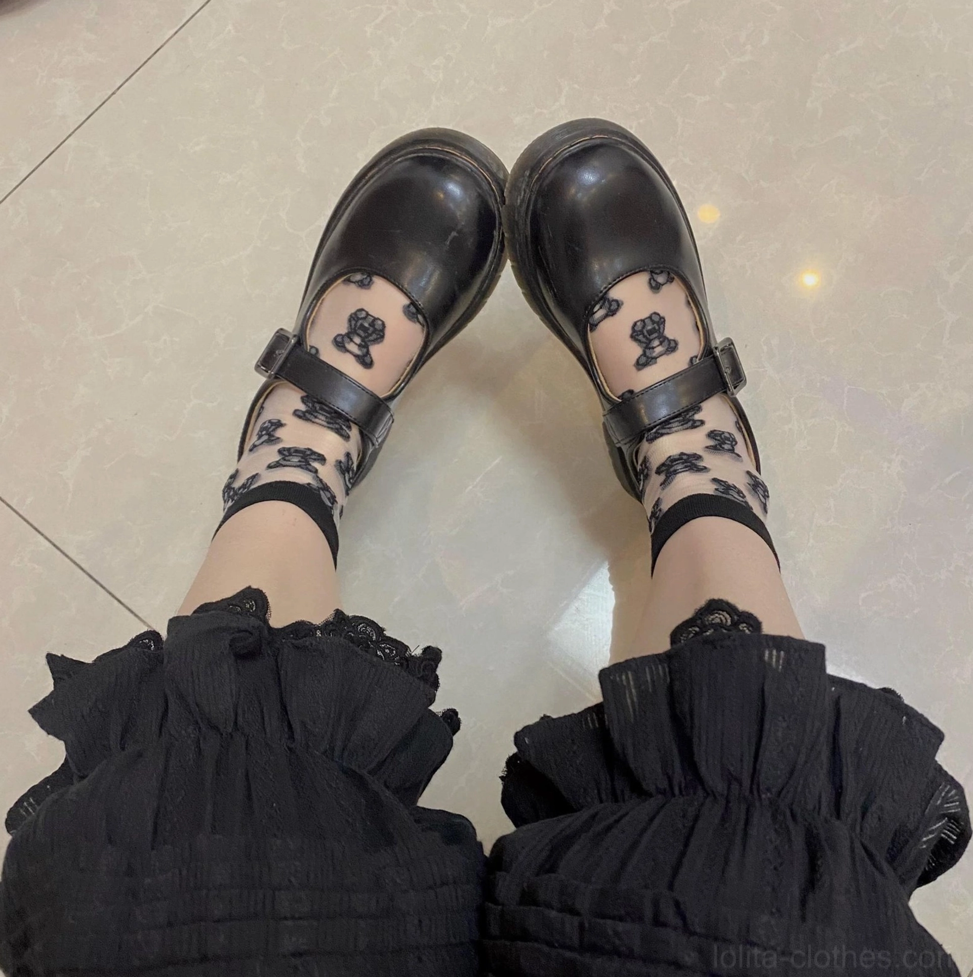 Overhead top-down close-up of lolita feet and black bloomers with ruffled hem worn with black mary jane flats and bear-patterned sheer stockings detail view