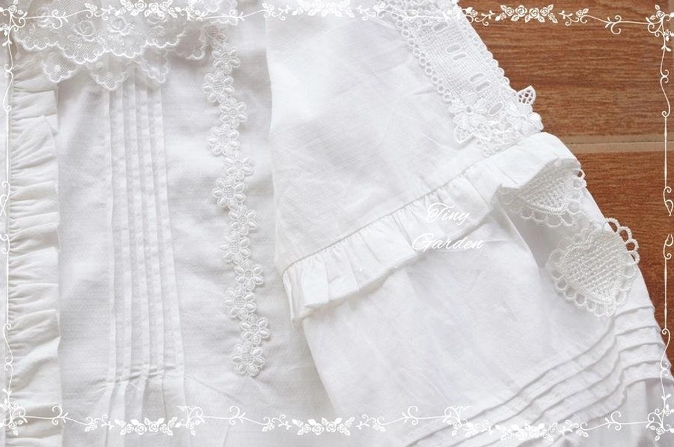 Flat lay close-up of black Lolita blouse front showing vertical pintuck stripes with lace appliqué and ruffled lace sleeve cuff details