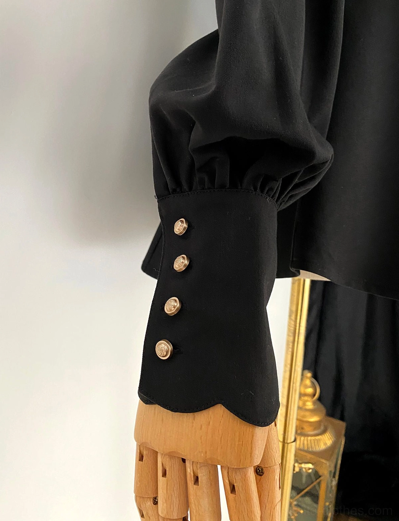 Black mutton sleeve Lolita blouse cuff close-up scalloped edge four metal buttons puff sleeve side view wooden hand