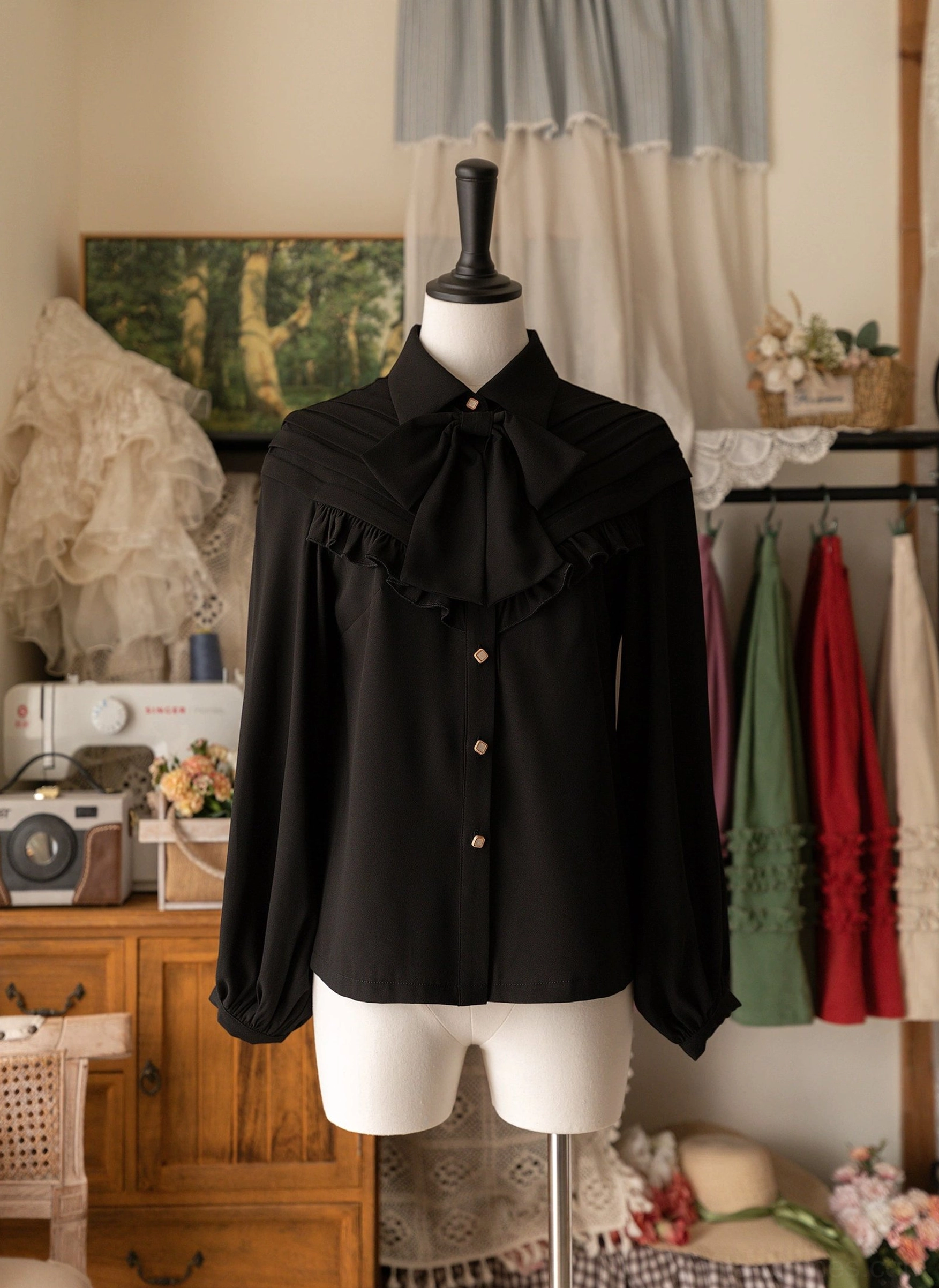 Black vintage Lolita bow blouse with statement bow necktie and ruffled front panel on dress mannequin, showing tailored long sleeves and slim metal front buttons in retro studio setting