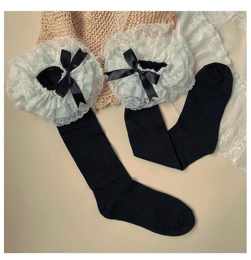 Black cotton Lolita socks pair overhead flat lay view white layered lace cuff with black satin bow solid black sock body lace woven mat