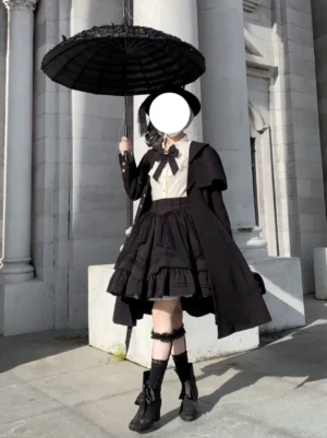 Black Classic Lolita coat with detachable cape front three-quarter view, Victorian tailored silhouette with oversized A-line hem, gold buttons, and dramatic cape collar on outdoor European architecture background