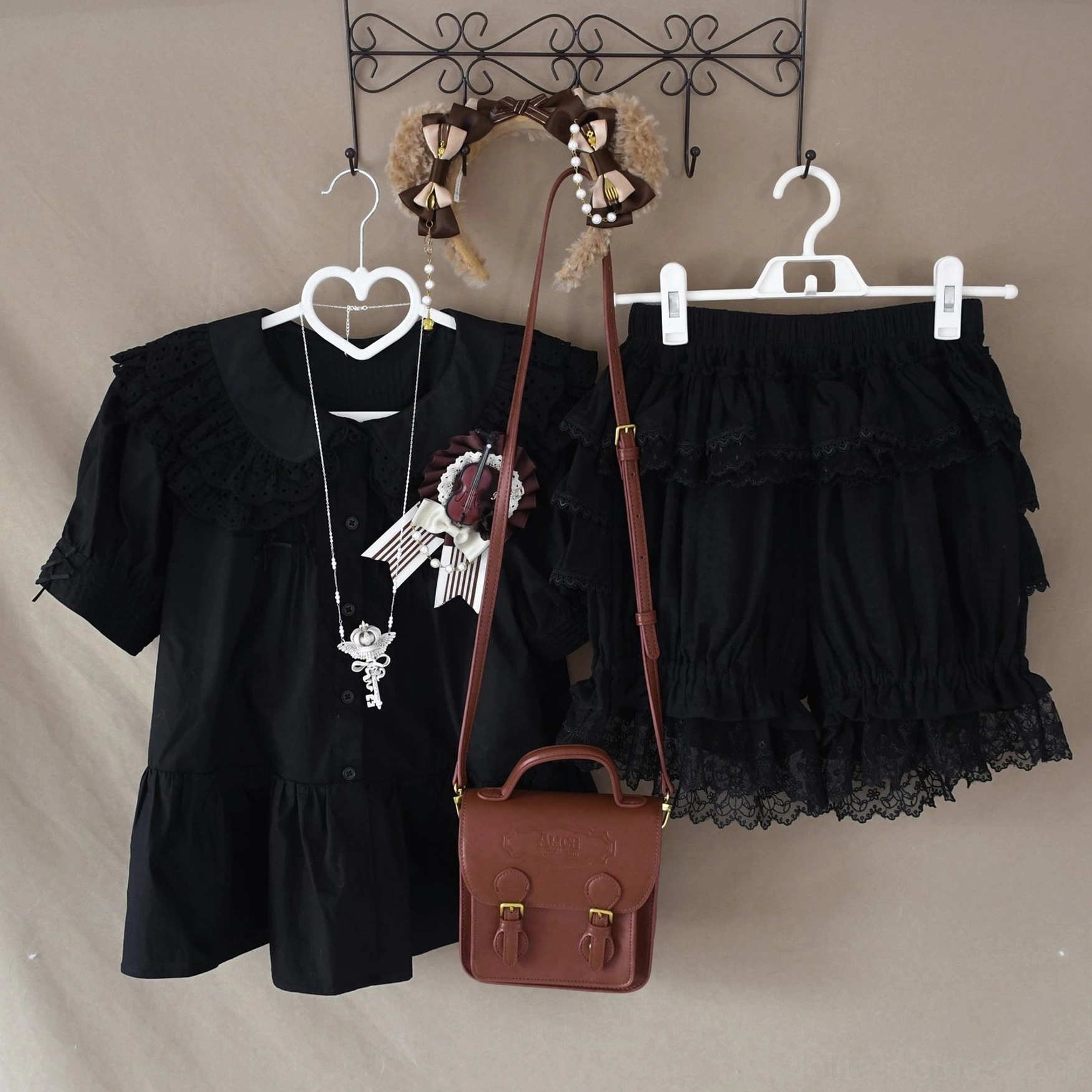 Black lolita coordinate set featuring blouse with doll collar and bloomer shorts with multi-tiered ruffles and black lace hem, hanging retail display with brown bag and hair accessories