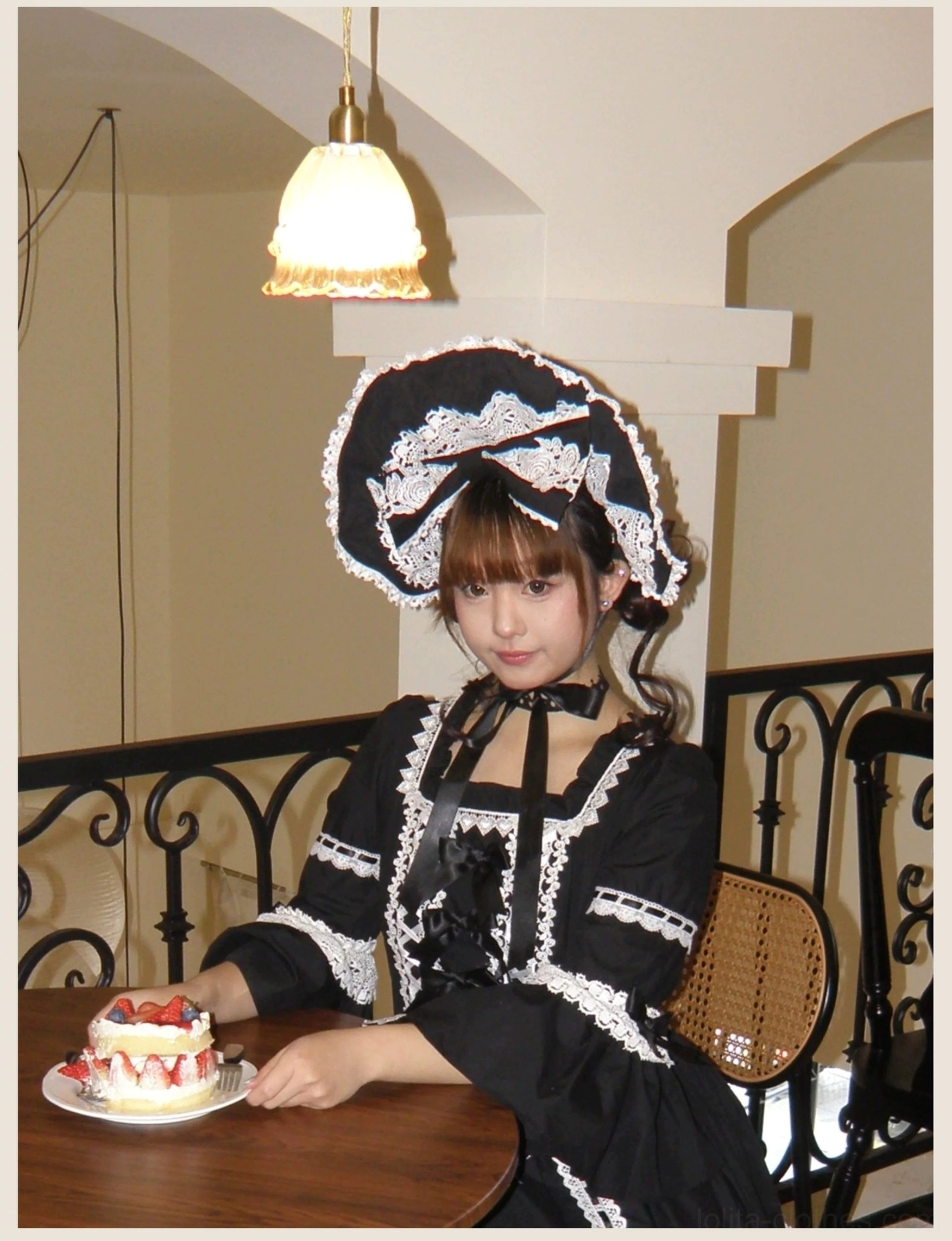Back body detail of black lolita dress showing lace-up back design with shirring, detachable waist tie, and layered white ruffled underskirt volume