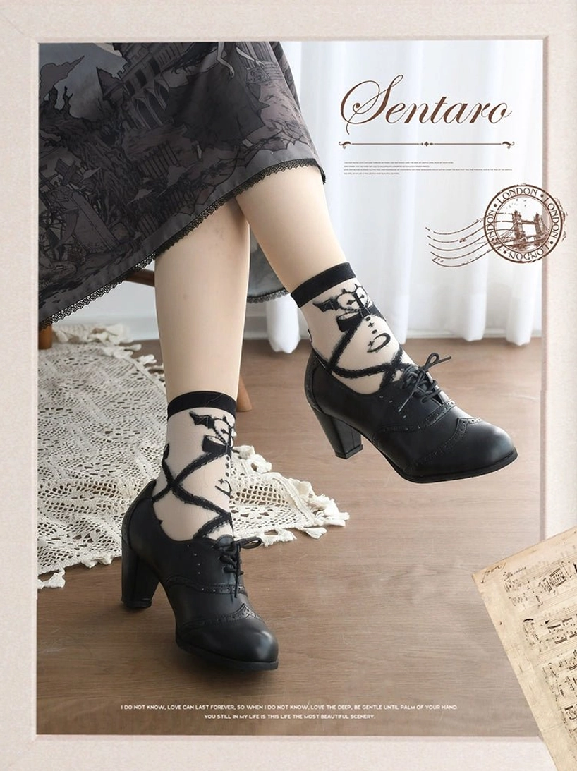Black matte lolita leather heel shoes with brogue perforations and ankle cross-strap design detail, side view showing block heel construction and refined silhouette