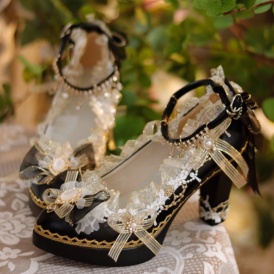 Pair of black luxury Lolita high heels with adjustable ankle strap black bow and large cream lace bows featuring gold details