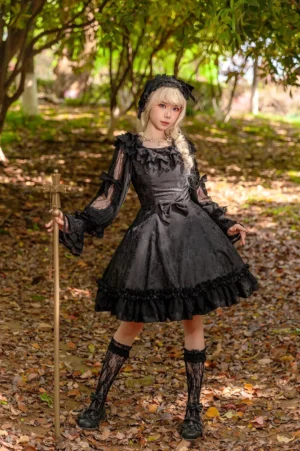 Black gothic lolita jumper skirt dress with fitted waist and flared A-line skirt, full body standing shot showing ruffled square neckline, lace stockings pairing, and autumn woodland background