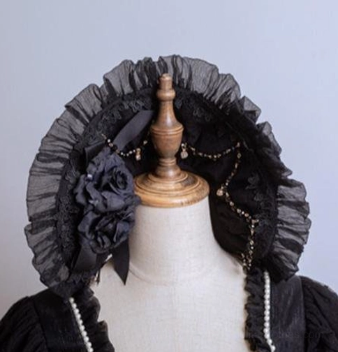 Black lolita lace bonnet headdress close-up featuring ruffled black sheer lace trim, large black fabric rose decor, pearl chain and bead embellishments on dress form mannequin