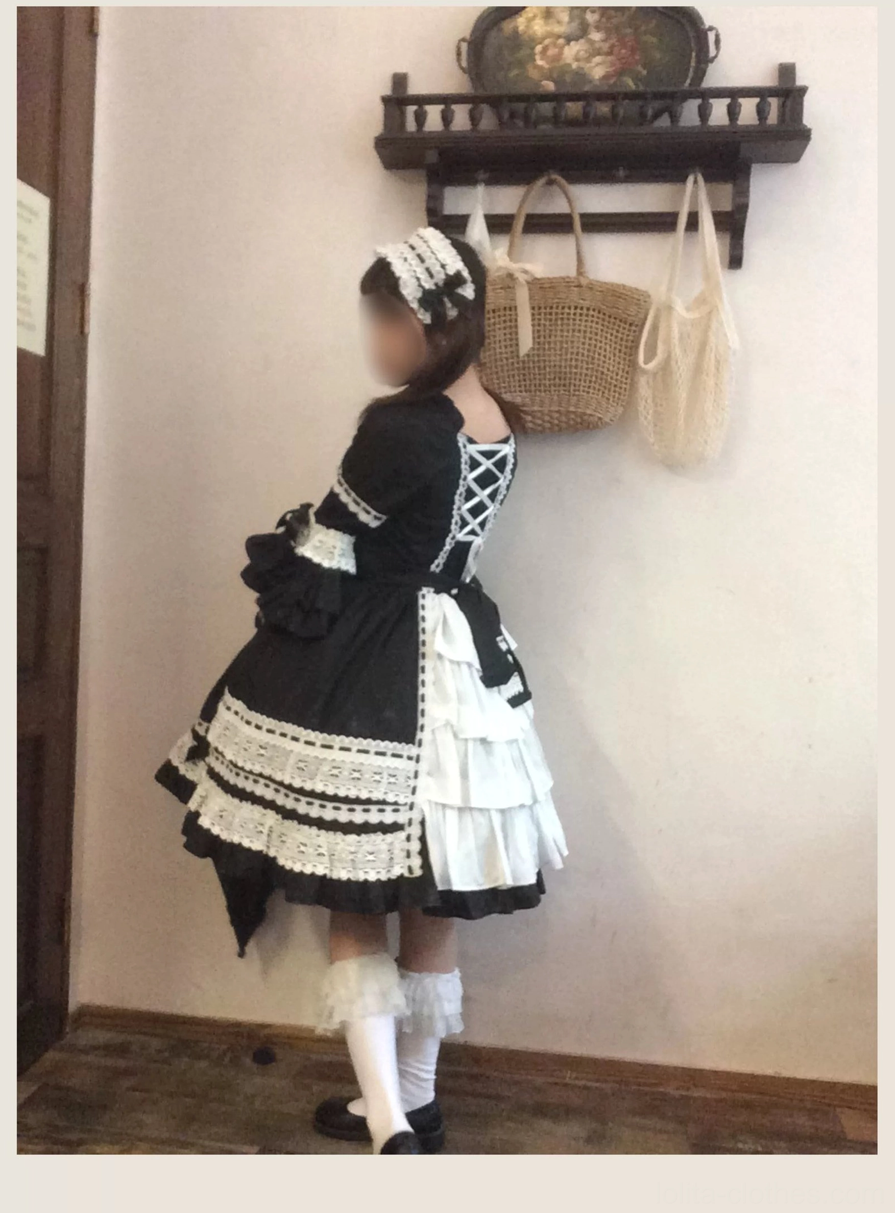 Back view of black old school lolita dress showing lace-up back closure, layered white ruffled underskirt, white leg warmers, and double-flounce updated cuff design