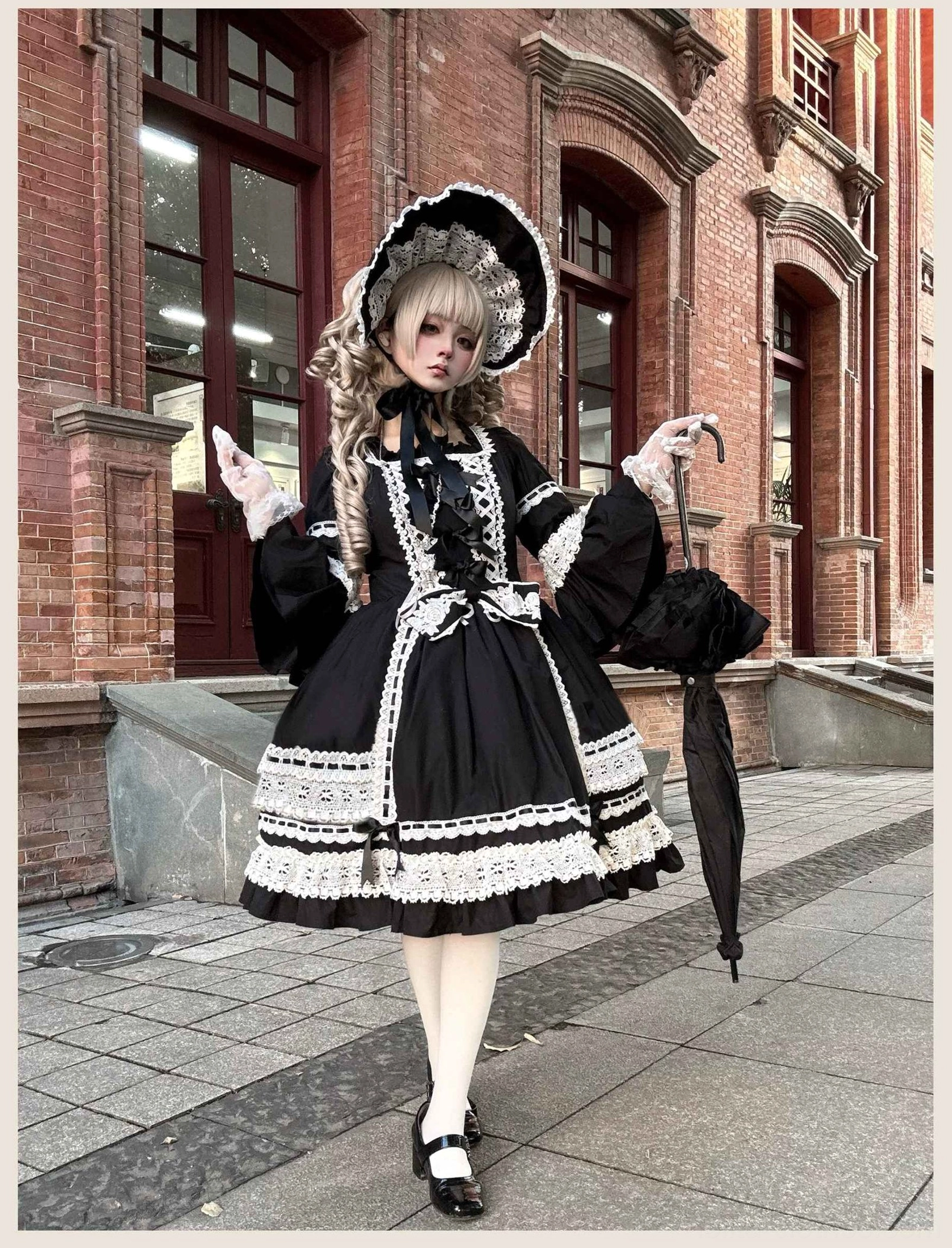 Studio detail shot of black lolita dress showing layered flounce hem construction, white ruffled underskirt, and back button placket detail