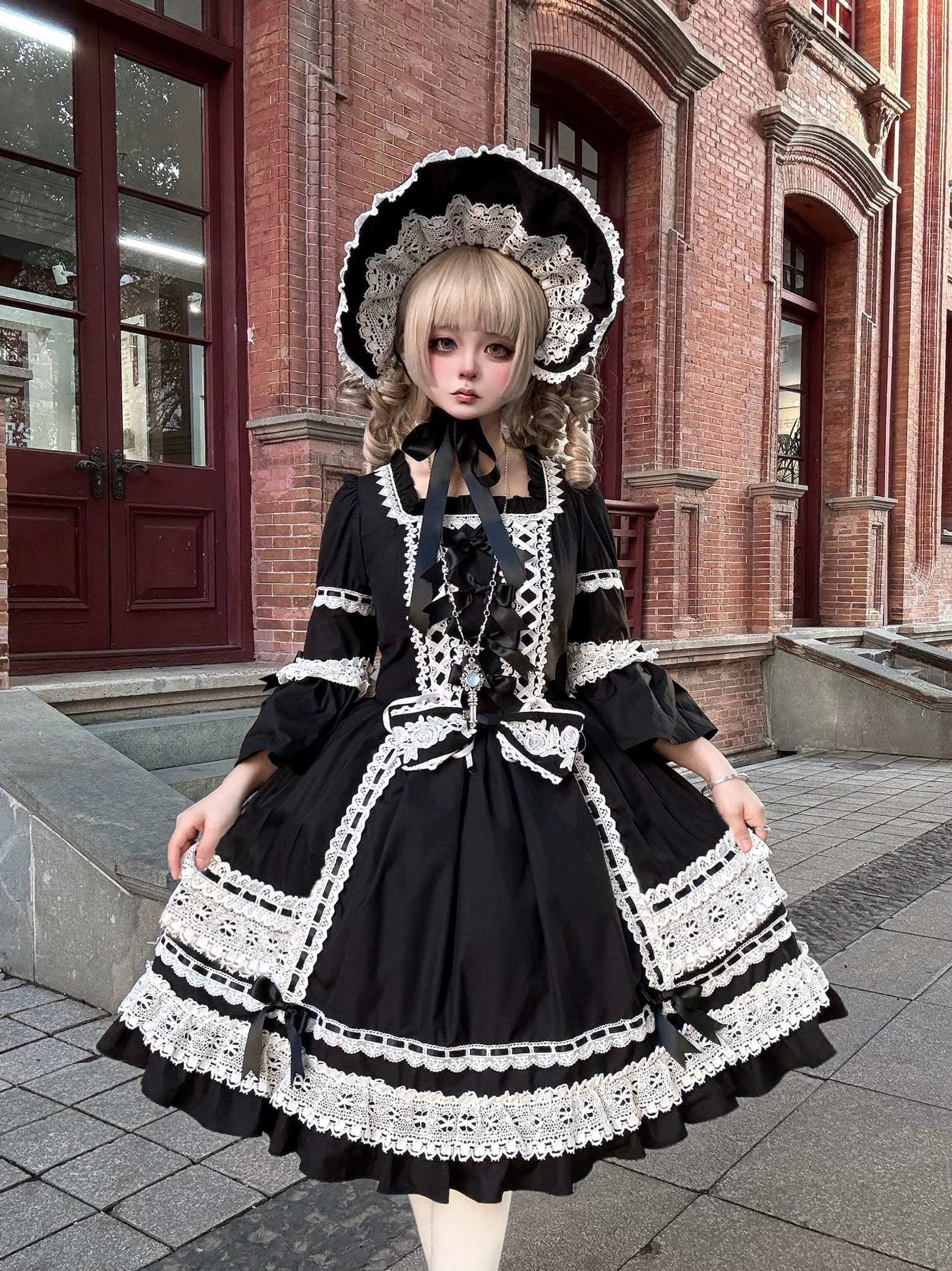 Detailed close-up of black lolita OP dress showing square neckline with lace, puffed three-quarter sleeves with lace hem, and structured bodice construction