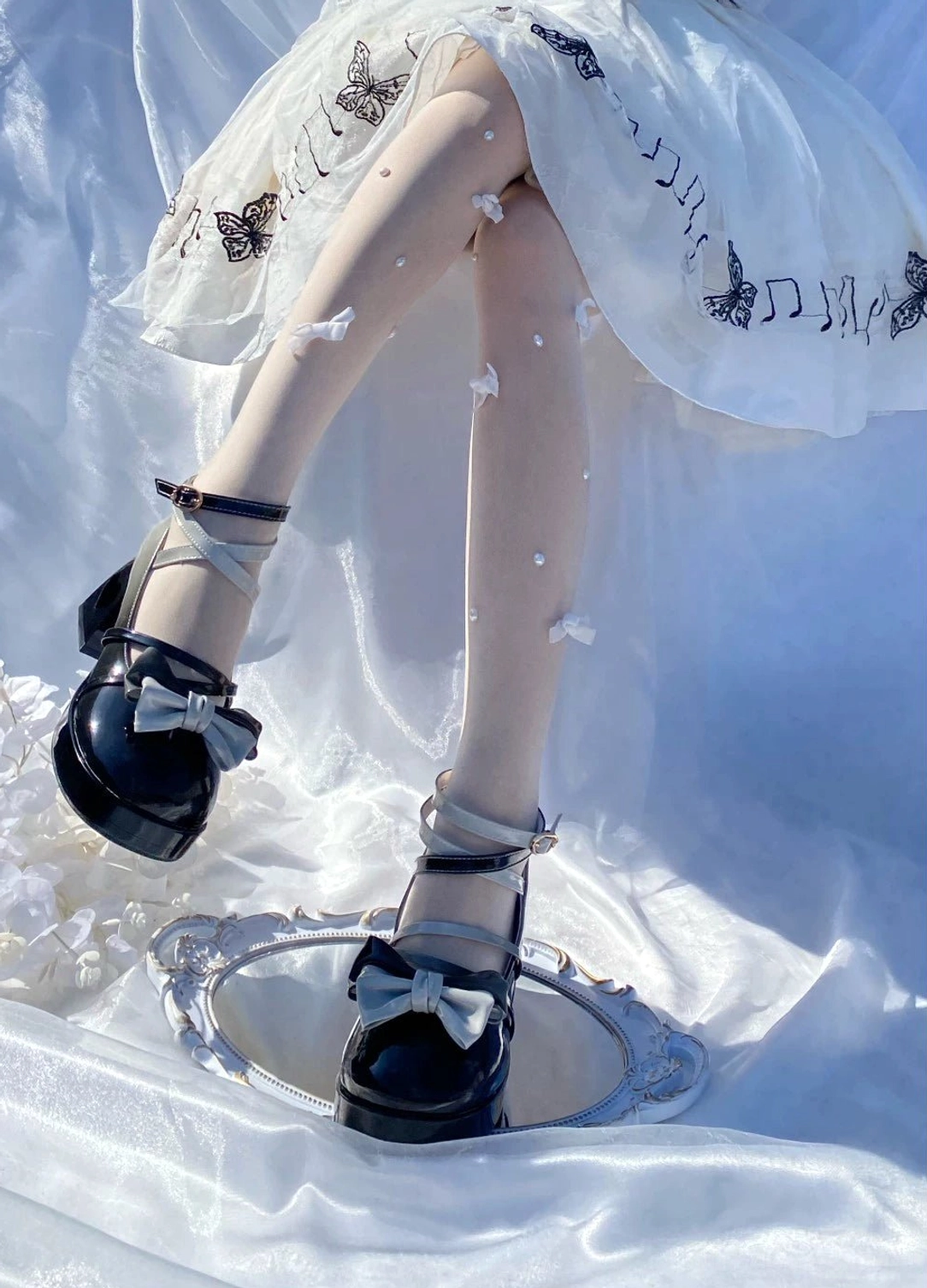 Black Sweet Lolita patent leather platform heels with glossy finish, heart-shaped heel cutout design, rounded platform toe, and cross ankle strap with bow for sophisticated Lolita coordination