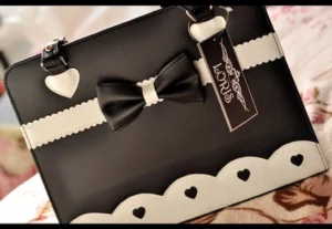 Classic black lolita shoulder bag with bow ornament white heart hardware scalloped trim overhead view