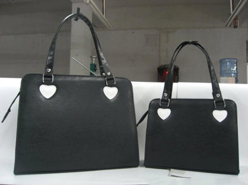 Pair of solid black minimalist lolita handbags with heart strap fixtures simple structured tote