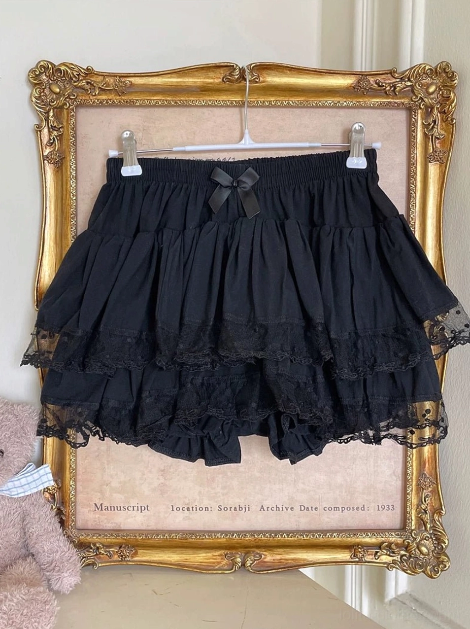 Black Lolita tiered bloomers hanging display on golden frame featuring solid black color full ruffle tiers refined lace trimmed hem and front elastic waist with decorative bow detail