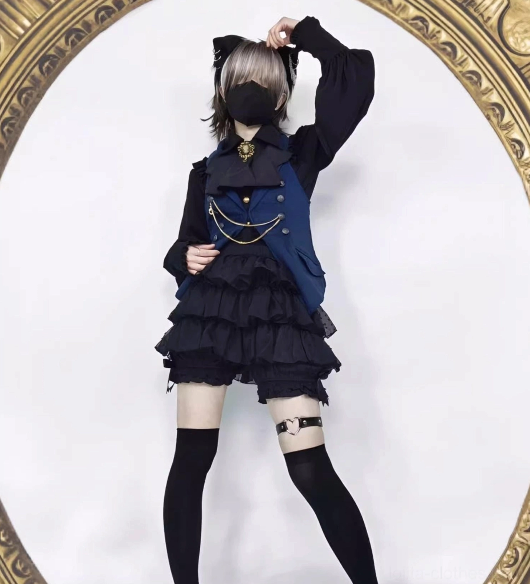 Male model wearing black tiered ruffle lolita bloomers thigh-high socks and gothic formal outfit with cat ear hair accessory full body front view dynamic styling