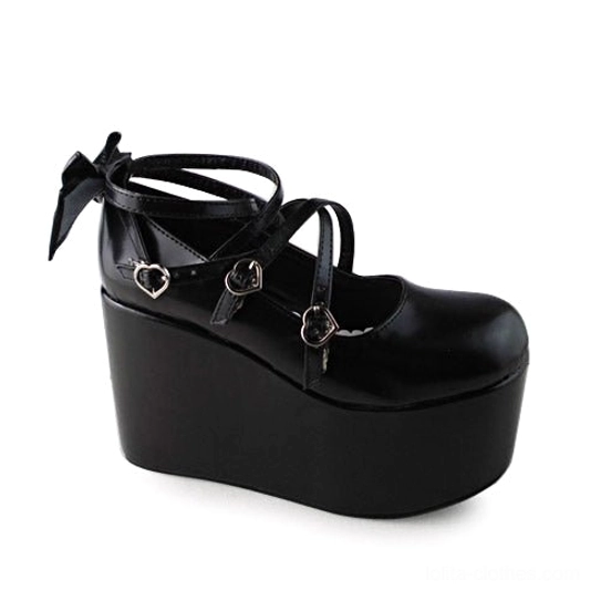 Black matte Lolita platform shoes side profile view displaying cross ankle straps with decorative heart buckles, thick wedge platform sole, and bow accents on toe and heel