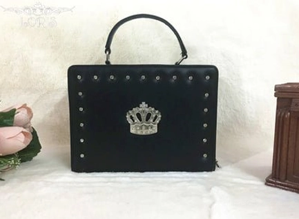 black matte studded gothic lolita crown handbag front flat lay display matte black pu leather metal round studs silver crown decor top carry handle white fuzzy backdrop