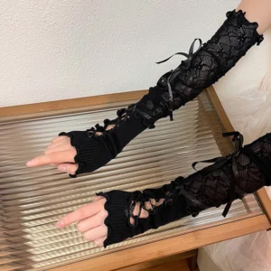 Black mesh lace Lolita arm sleeves with satin ribbon bows and fingerless cutout design displayed on wooden tray tabletop photography