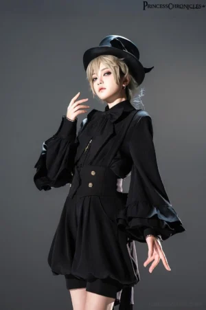 Model wearing black Ouji Lolita coordinate with detachable bow tie shirt, bishop sleeves, black top hat, and matching high-waisted shorts creating complete prince lolita aesthetic