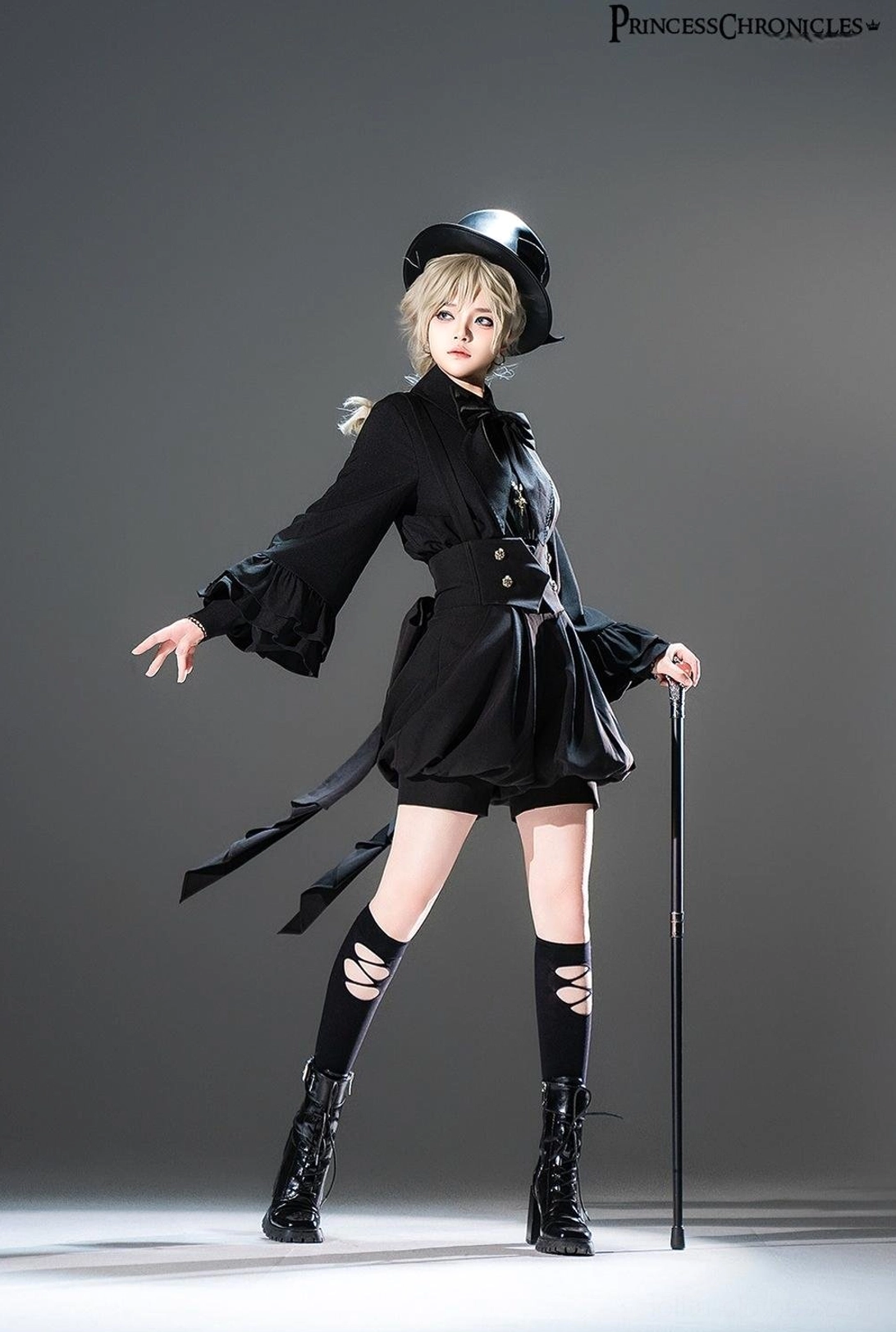 Full body side view of black Ouji Lolita outfit featuring detachable bow tie shirt, platform boots, knee-high socks, walking cane, and long back waist sash for gothic aristocratic look
