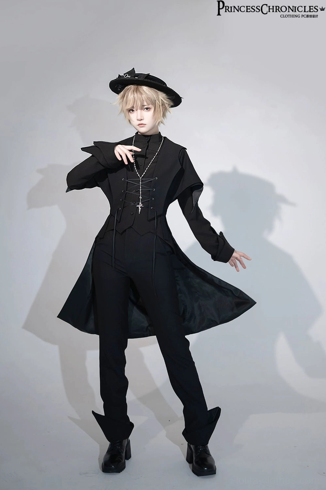 Slightly side full-body front view of black Ouji Lolita swallowtail vest worn by blonde studio model with black bow hat, showing structured lace-up corset front and formal tailored silhouette