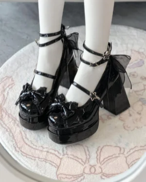 Glossy black classic lolita platform heels with ethereal tulle bow at heel collar, decorative front bow, dual black ankle straps with star buckles, top-down overhead view showing platform construction