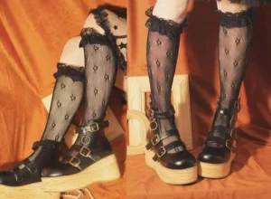 Pair of black patent leather retro Lolita platform shoes with dual buckle ankle straps and thick wooden platform soles, front close-up view with matching fishnet stockings