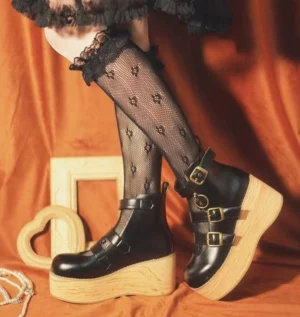 Black glossy patent leather retro Lolita platform ankle boots with double metal buckle straps and chunky wooden wedge sole, styled with lace-trimmed fishnet stockings
