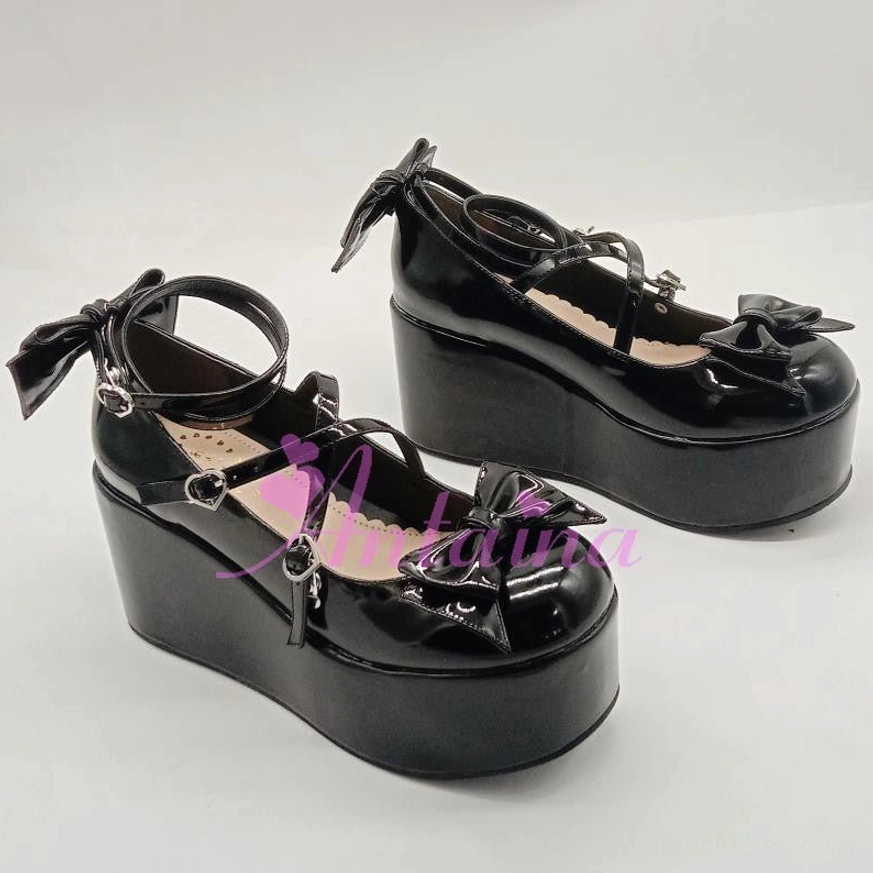 Black patent leather Lolita platform shoes with decorative toe bow and heart-shaped ankle buckles, flat lay front view on white background showcasing high waterproof platform sole