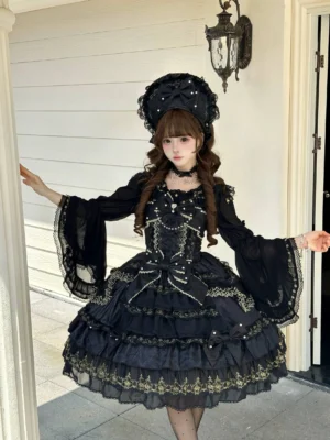 Black Gothic Sweet Lolita JSK dress with pearl details and layered gold lace ruffles, modeled in European residential doorway with matching bonnet, full-body front view showcasing flared sleeves and beaded chest decoration