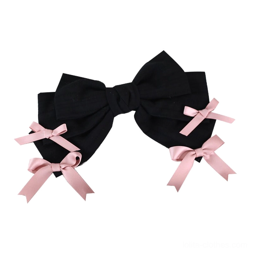 Black bowknot hair clip for sweet lolita outfits flat lay showing large black bow with two small pink bows on each side
