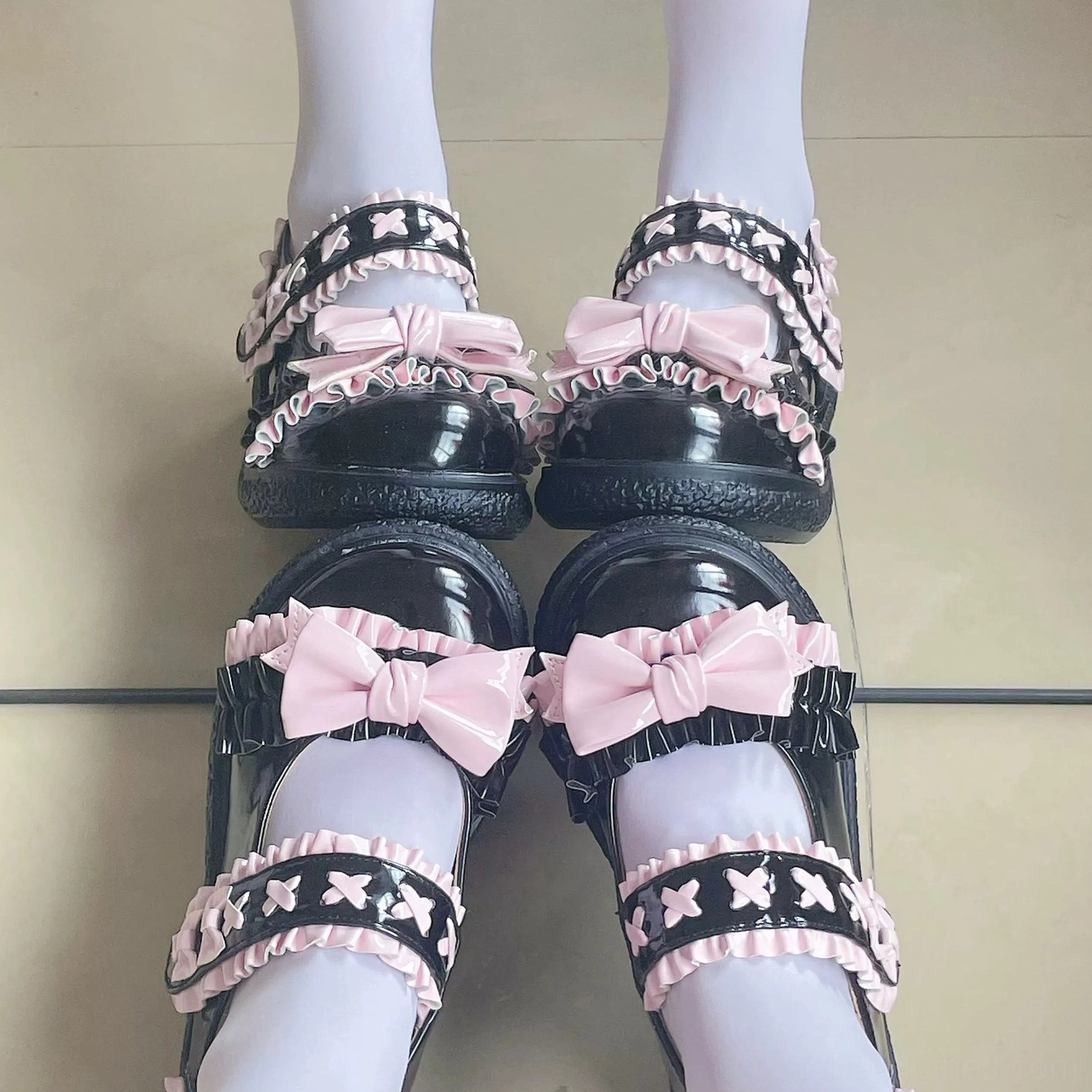 Overhead flat lay of black-pink Lolita Mary Jane shoes on tiled floor with light purple stockings, dual ruffled star straps and pink satin bows with round toe flats