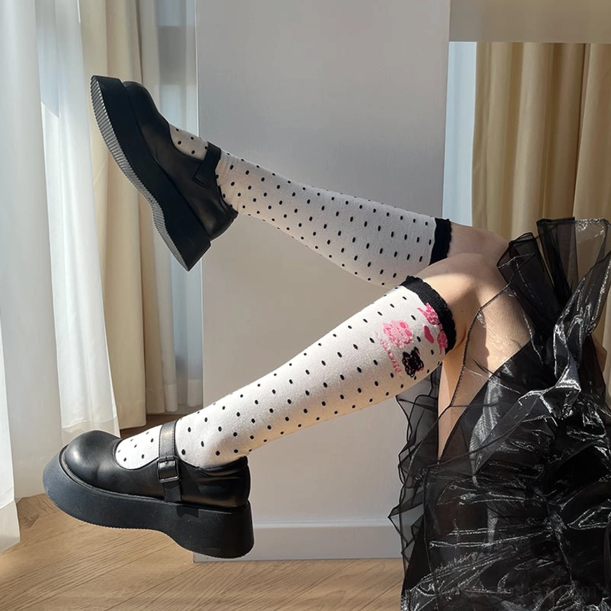 Black polka dot lolita calf socks worn with black platform Mary Janes and sheer outfit showing ribbed cuff and bear graphic print