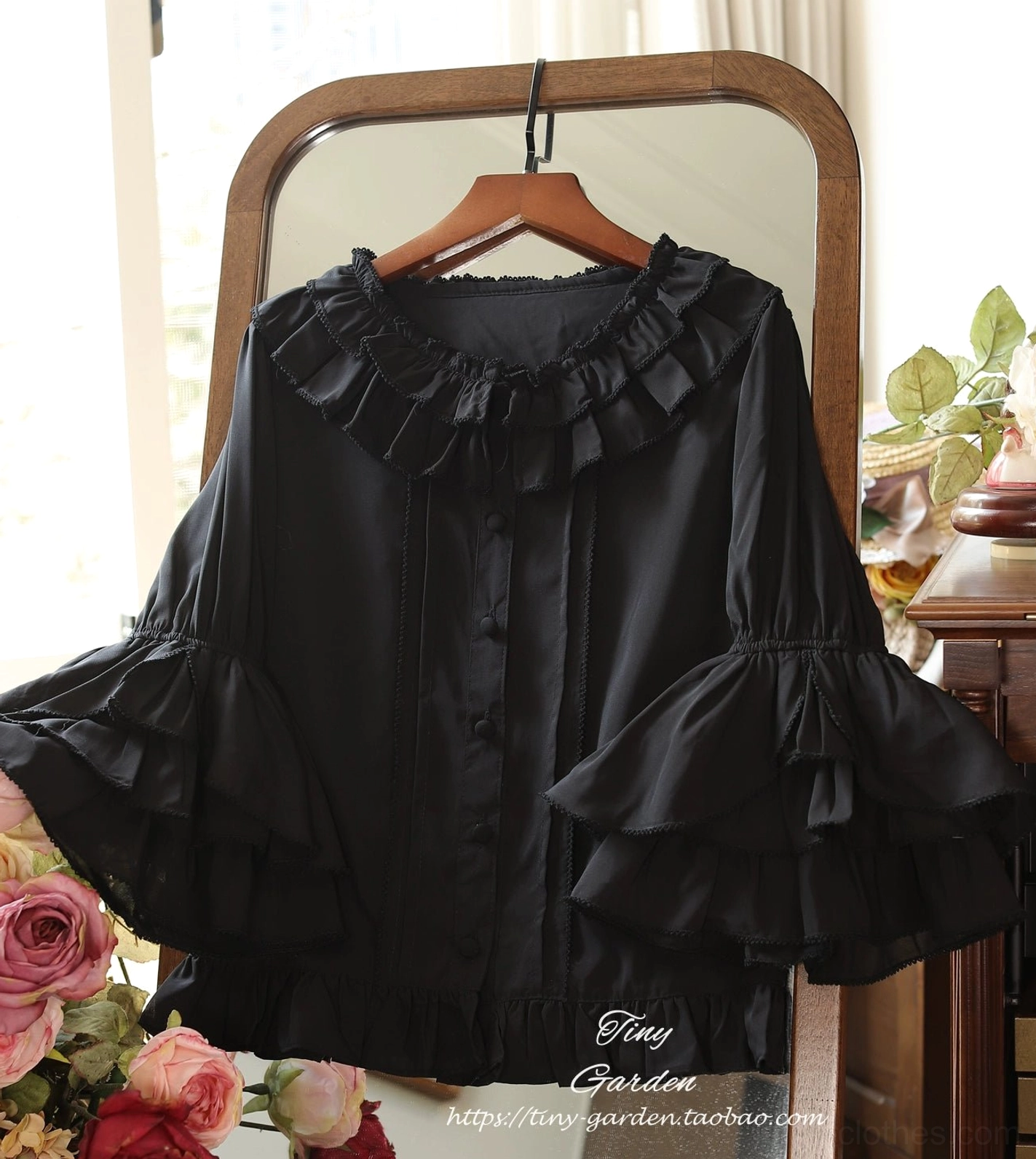 Black vintage ruffled lolita blouse with round ruffled collar and layered bell sleeves, hanging front display with retro mirror and flower background, picot trim version design