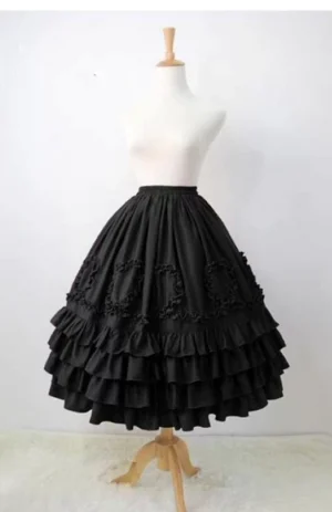 Black ruffled Lolita underskirt with heart-shaped fabric trims and layered ruffle hem on wooden dress mannequin showing full A-line silhouette front view