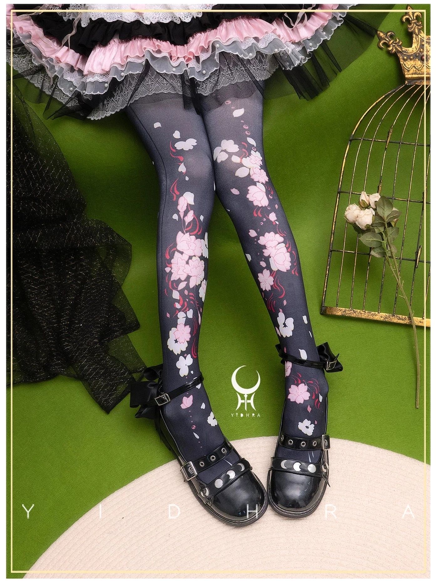 Black sakura print Lolita pantyhose 120D with pink and white cherry blossom design paired with dark pink and black frilly Lolita skirt and black bow Mary Jane shoes on decorative background with birdcage