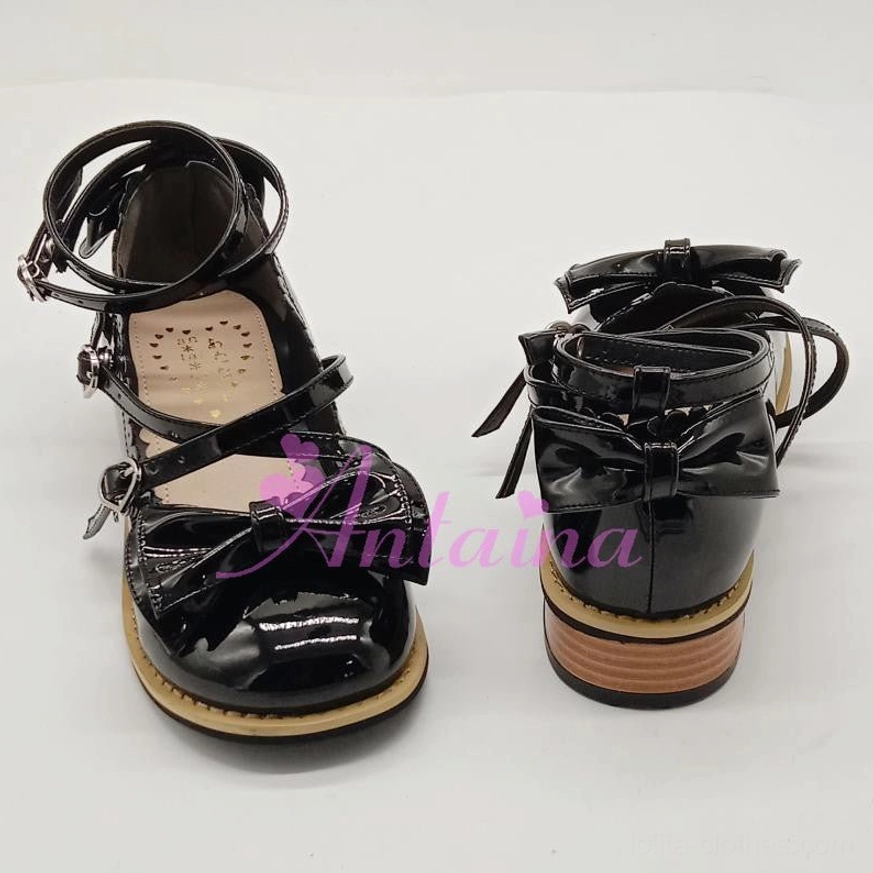 Shiny black patent leather lolita tea party shoes with bow accents on toe, buckle fastener straps, tan edged low block heel - front and rear three-quarter view